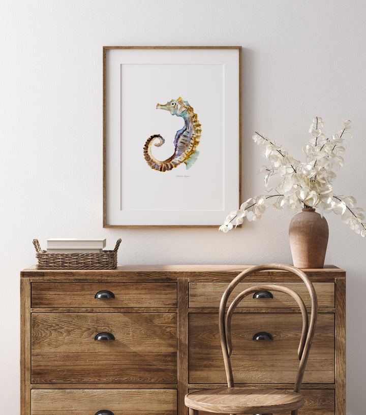 Zeepaardje aquarel schilderij in houten frame boven houten kastje