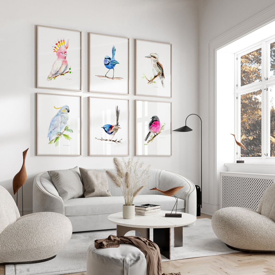 Modern living room with a white sofa, armchairs, and wall art of colorful birds.
