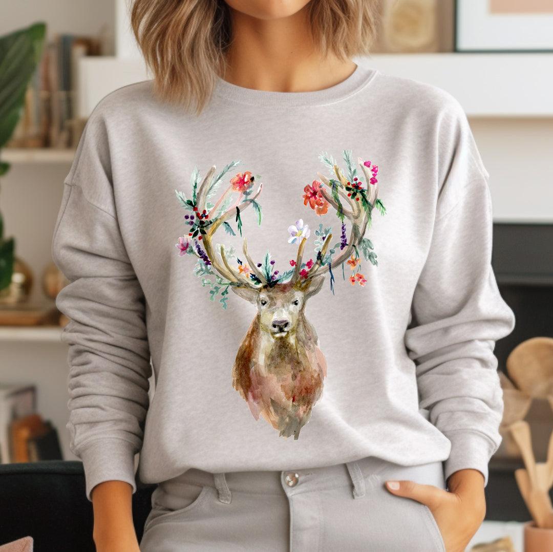 Person wearing a gray sweatshirt with a deer design featuring floral antlers.