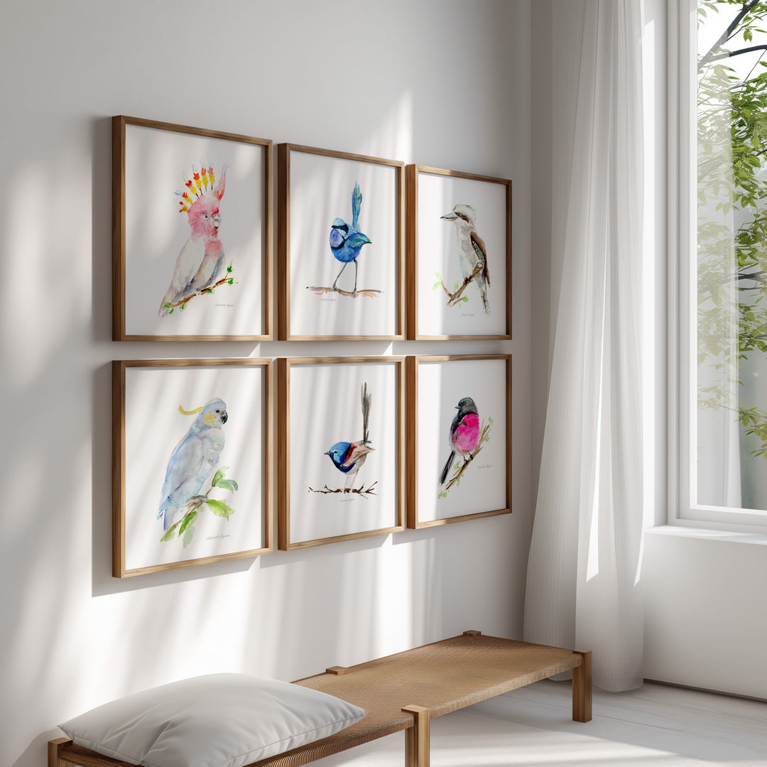 Framed artwork of pink, blue white birds on a wall in a bright room with a bench and window.