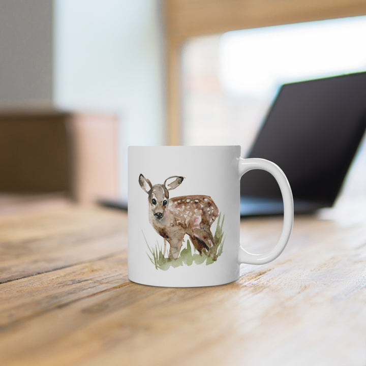 White mug with a deer illustration on a wooden surface