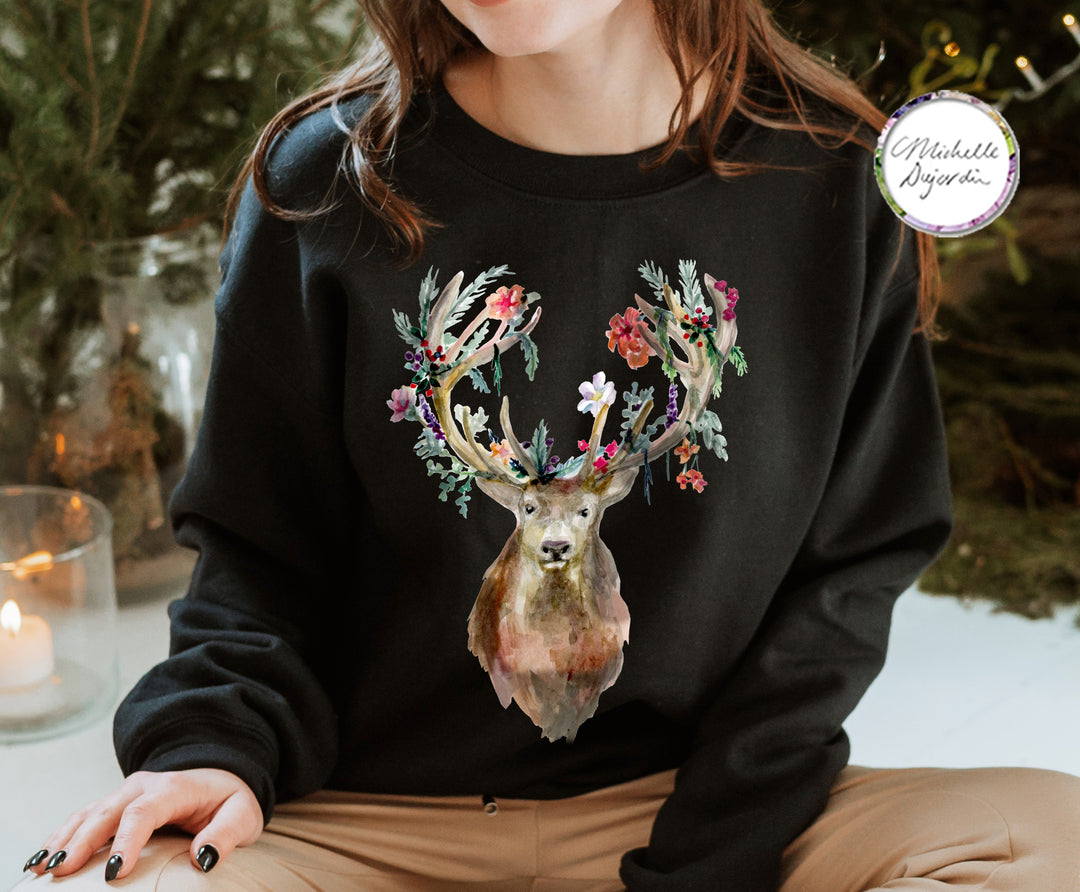 Person wearing a black sweatshirt with a floral deer design, sitting in a cozy indoor setting.
