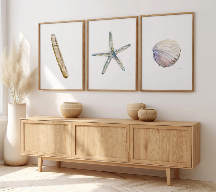 Wooden sideboard with decorative items and framed sealife artwork on a wall.