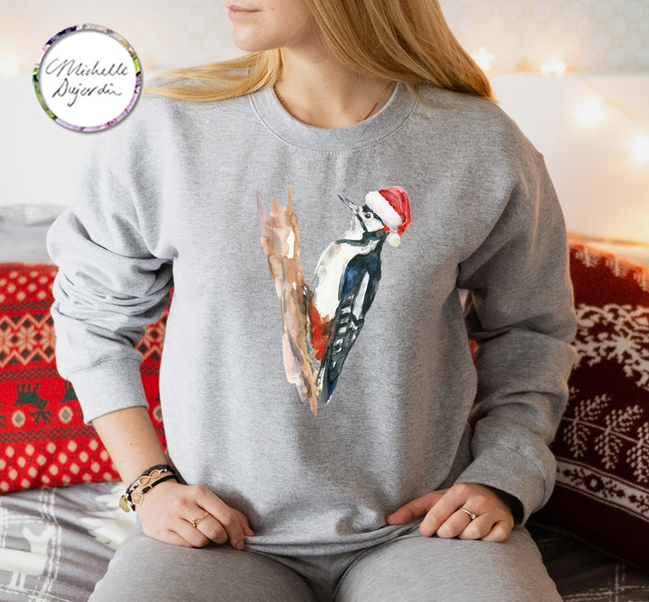 Person wearing a gray sweatshirt with a Christmas-themed design of a bird and a hat.