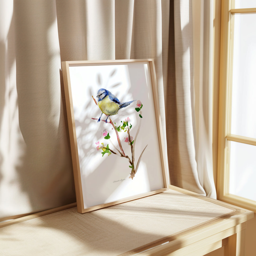 Framed artwork of a bird on a branch in a bright room with curtains