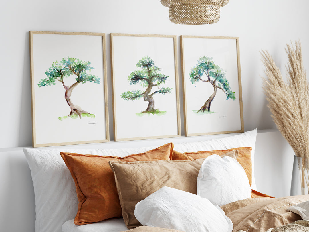 Three framed tree prints above a sofa with decorative pillows.