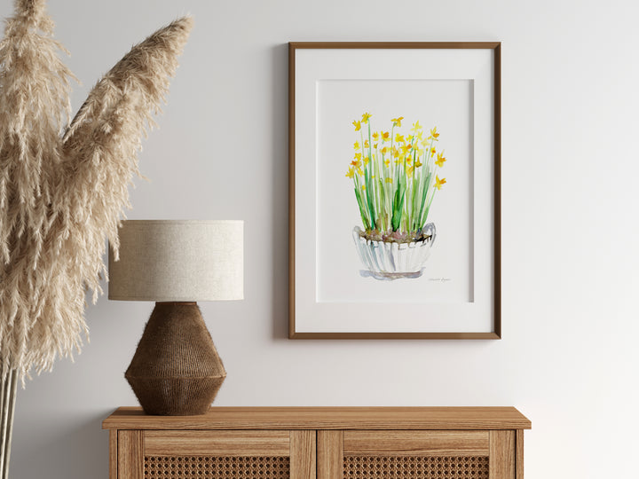 Framed artwork of daffodils on a wall above a wooden cabinet with decorative elements.