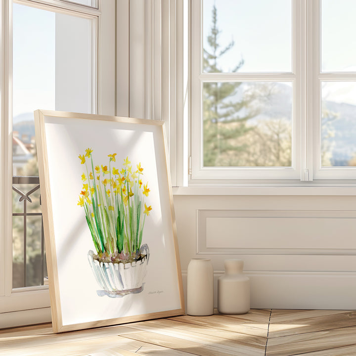 Framed artwork of yellow flowers on a wall with large windows in a bright room.