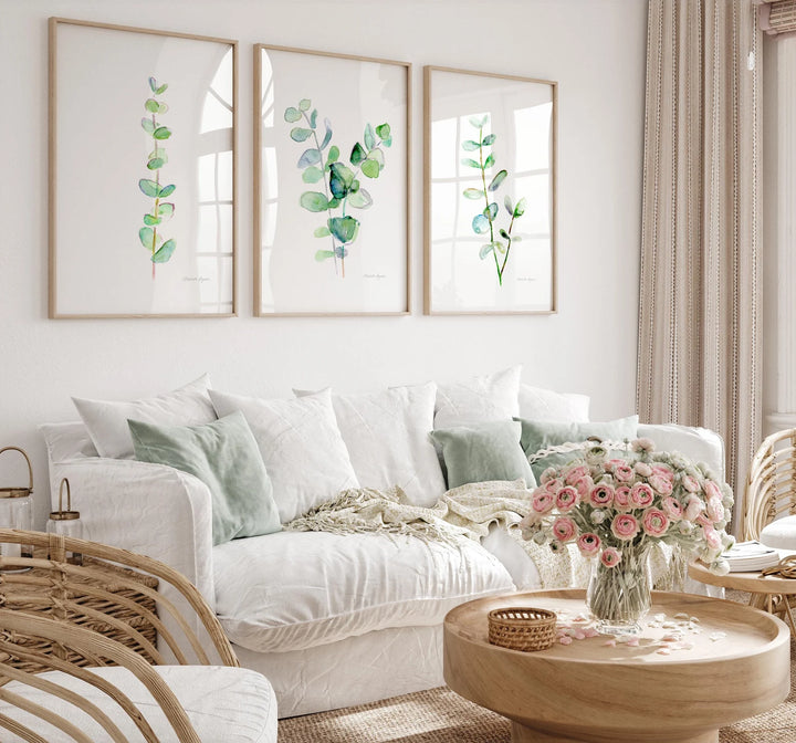 Living room with a white sofa, framed artwork, and a coffee table with flowers.