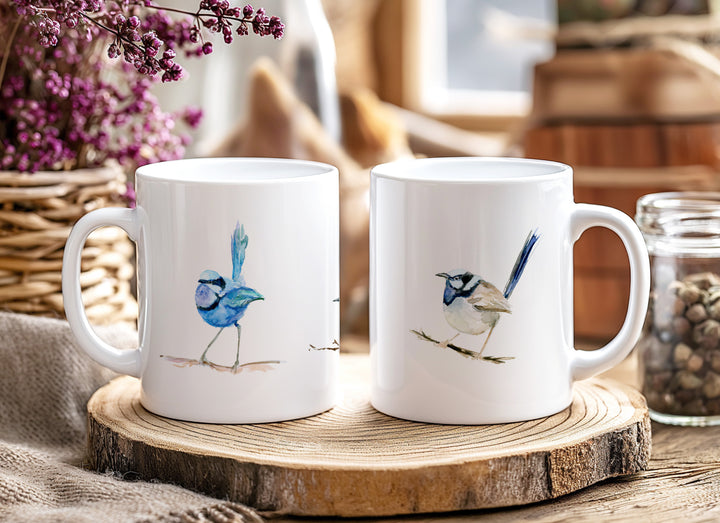 Two white mugs with bird illustrations on a wooden coaster, surrounded by decorative elements.
