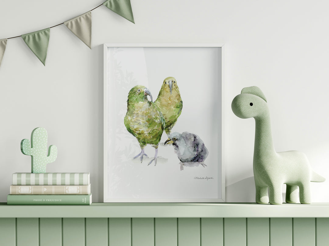 Framed artwork of two green Kea birds on a shelf with decorative items.