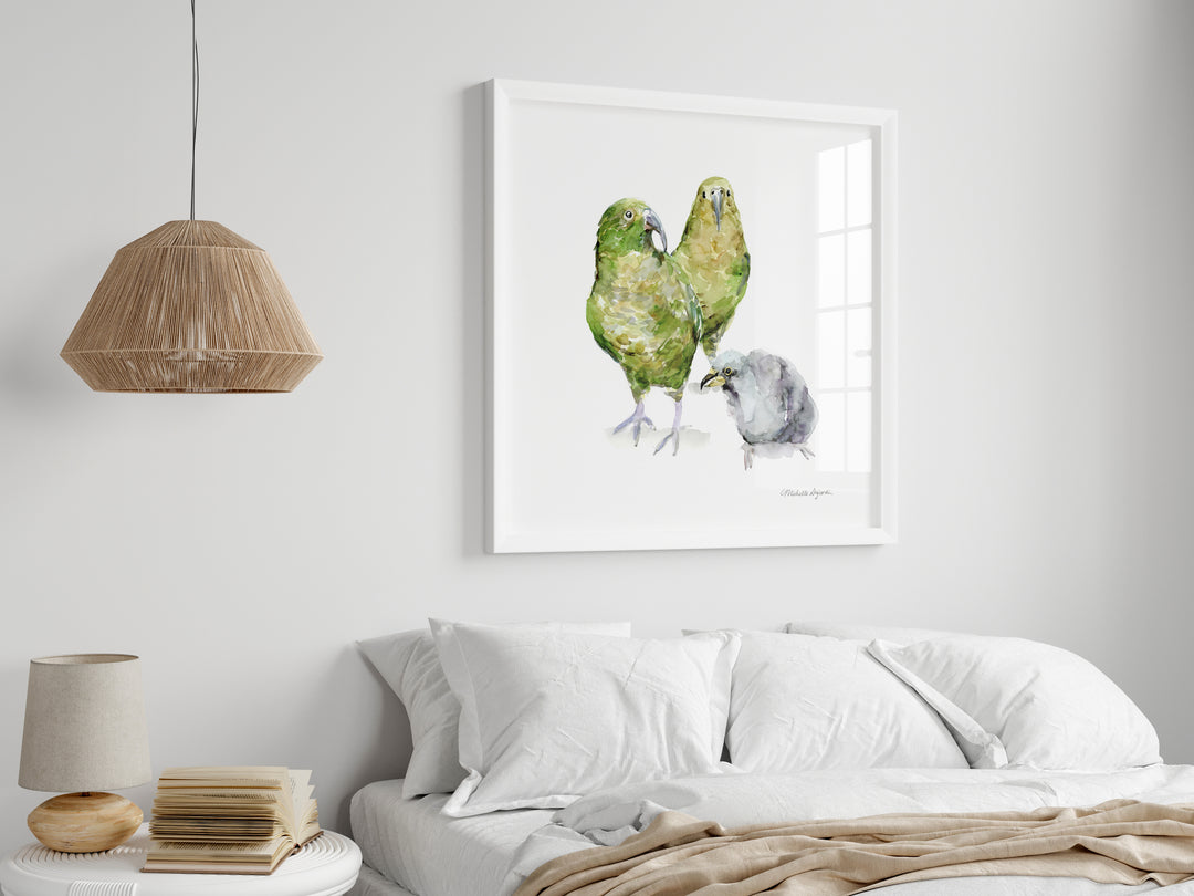 Framed artwork of two green parrots and a gray bird on a white wall above a bed.