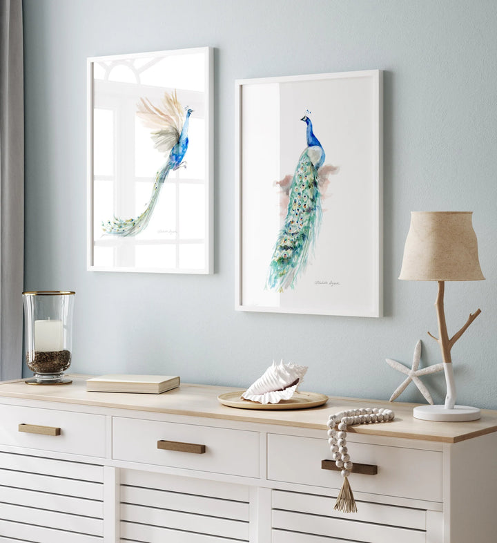 Two framed peacock artworks on a wall above a wooden console table with decorative items.