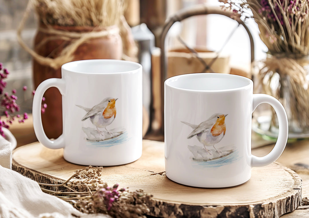 Two white mugs with bird illustrations on a wooden surface.