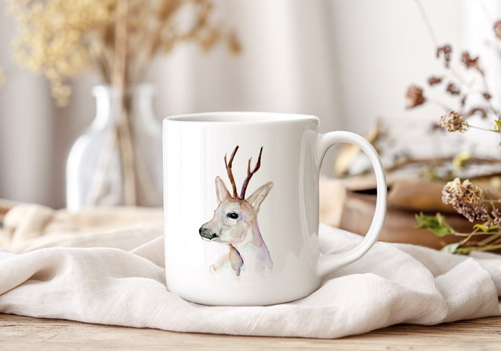 White mug with a deer design on a white surface with decorative elements.