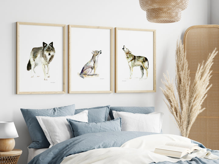 Drie ingelijste prints van wolven aan de muur boven een bed  met blauw dekbed