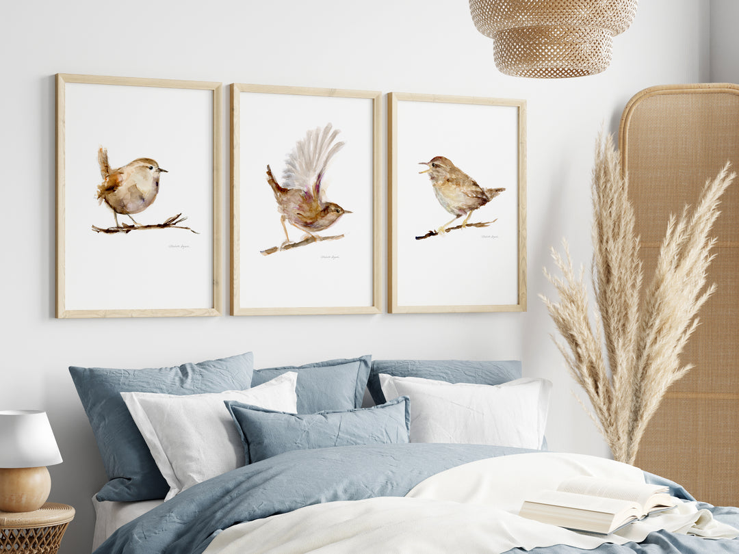 Three framed bird prints above a bed with blue bedding and white pillows.